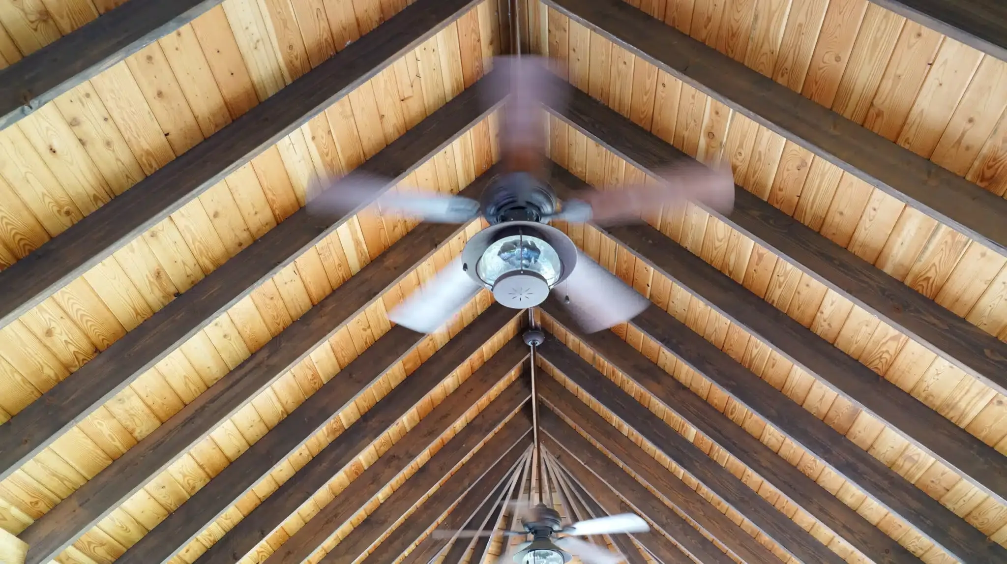 spinning ceiling fan attached to wooden vaulted ceiling