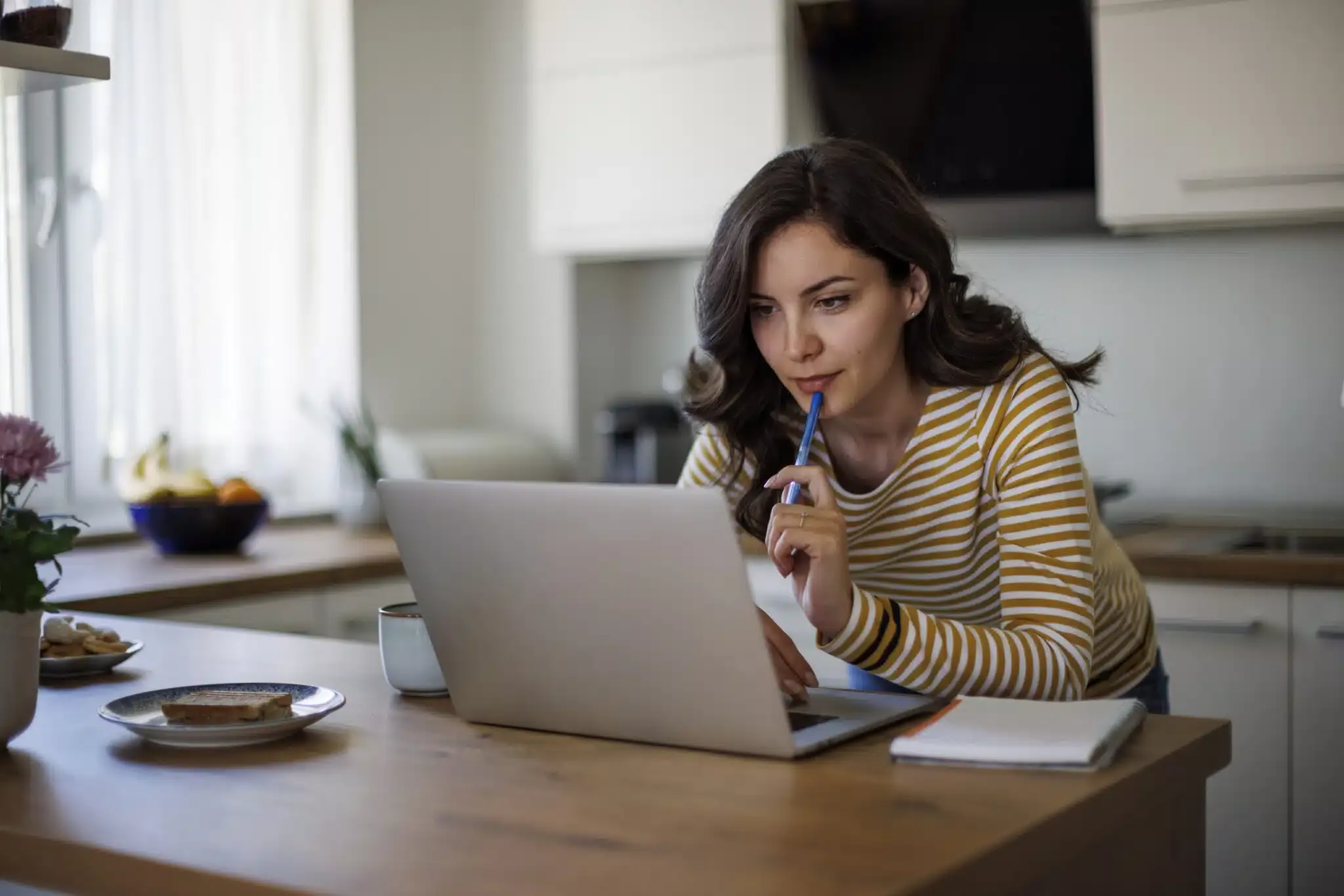 woman leaning on counter looking at laptop