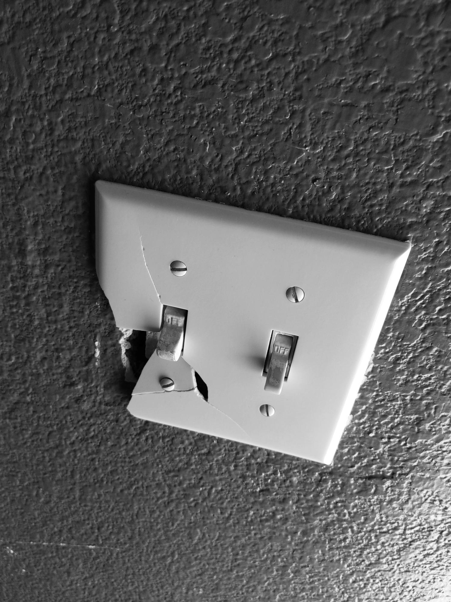 broken light switch cover on gray textured wall