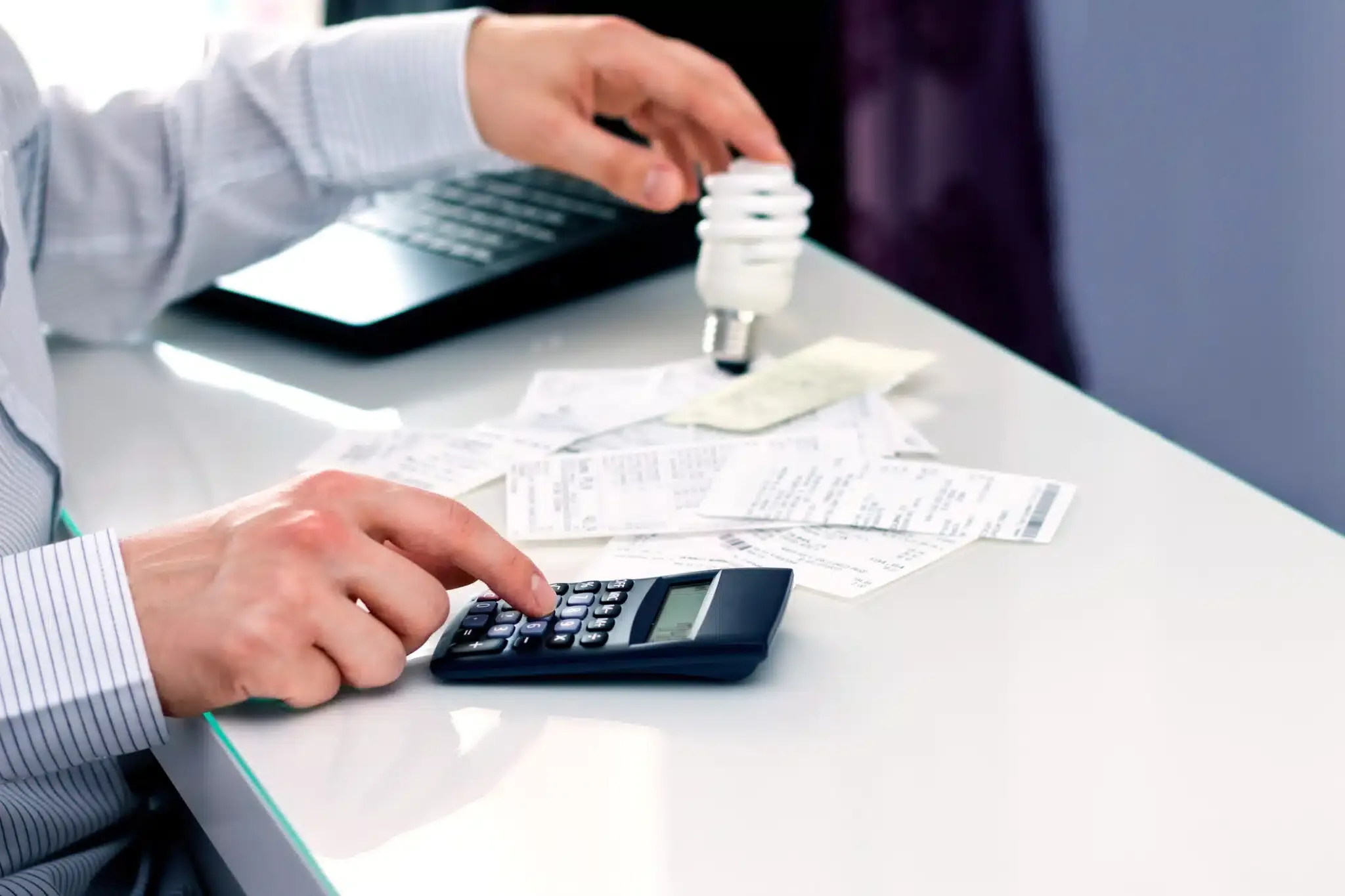 hand holding light bulb and typing on calculator