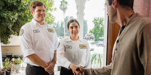 Two Mister Sparky electricians shaking homeowner's hand