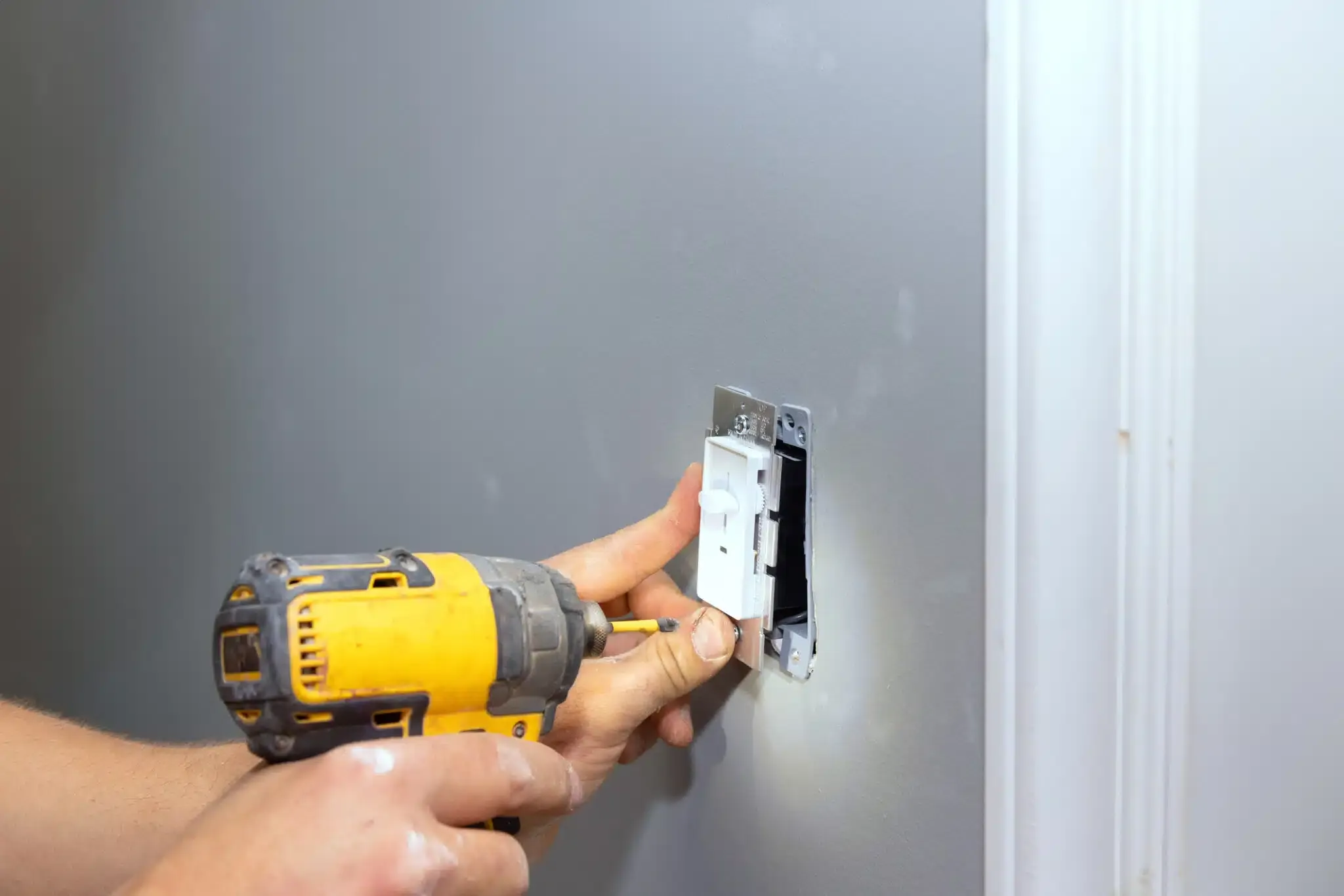 hands using drill to install light switch