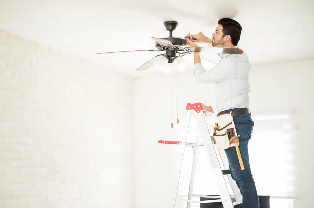 electrician using screwdriver to install ceiling fan