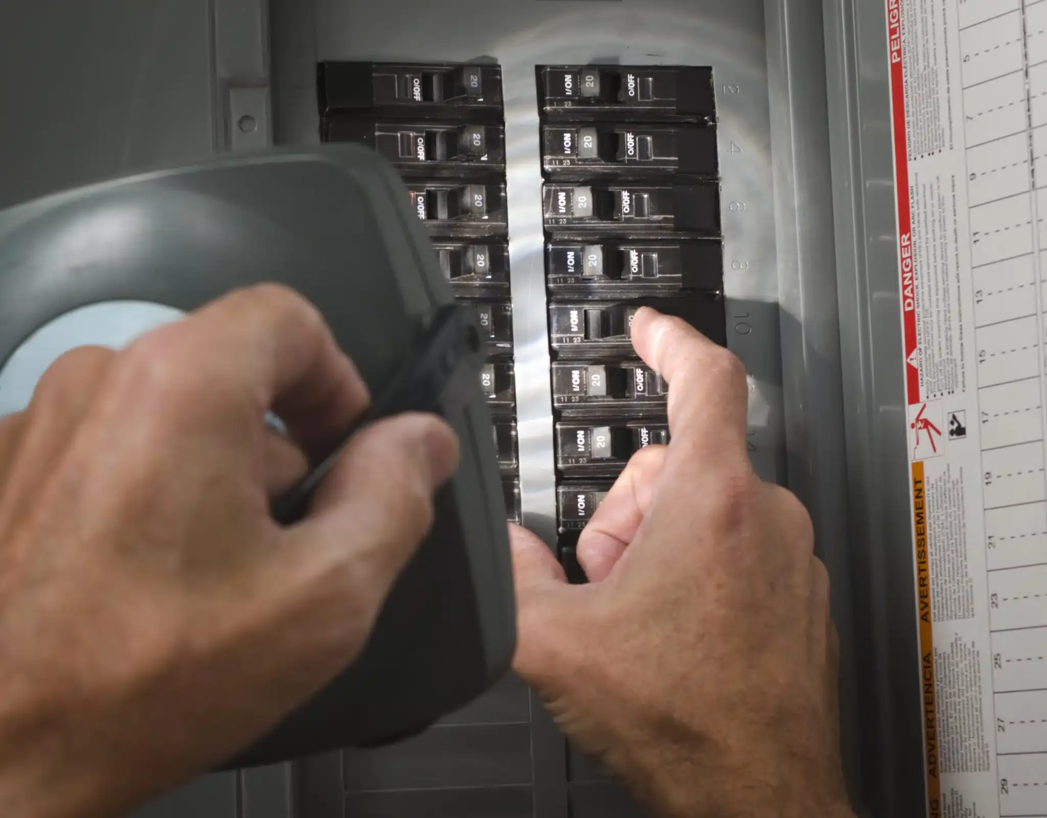 hands flipping switch on circuit breaker