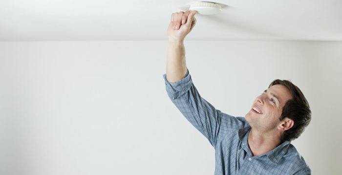 Homeowner checking smoke alarm